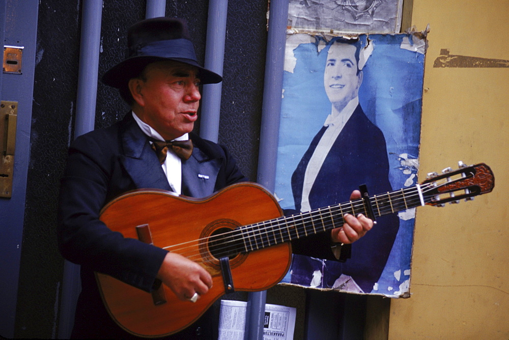 A guitar player strumming for impromptu tango dancers in Buenos Aires' San Telmo Square.