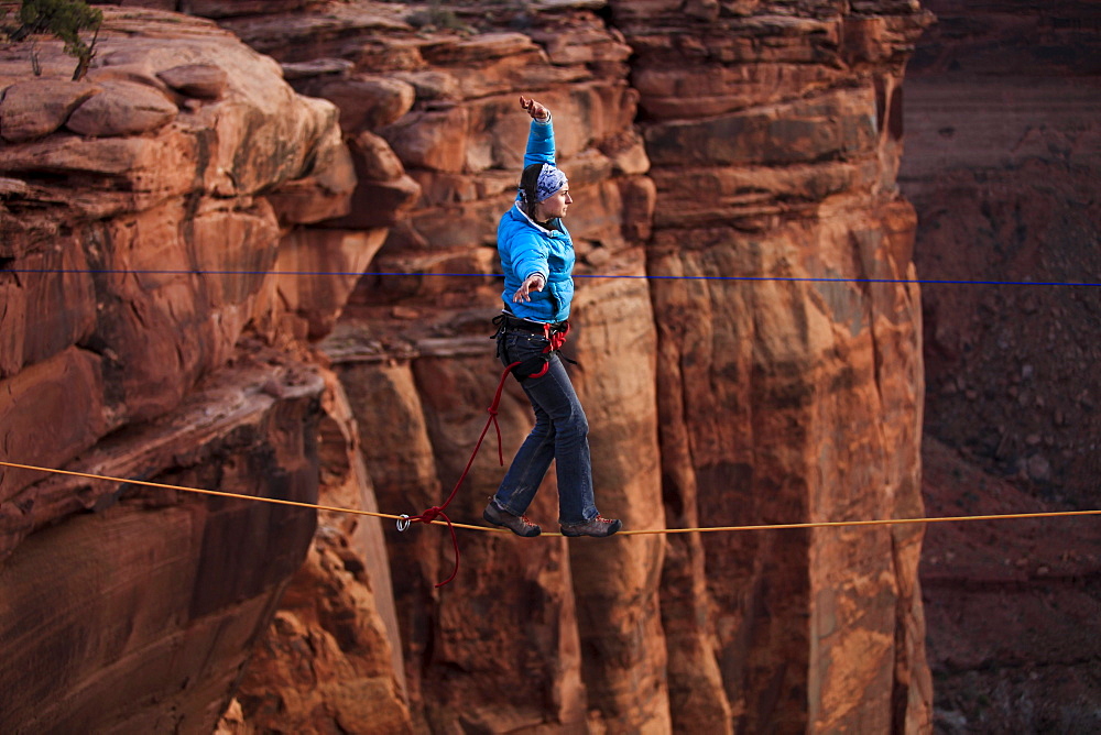 A female highliner walks across a highline at the Fruit Bowl in Moab, Utah, USA.