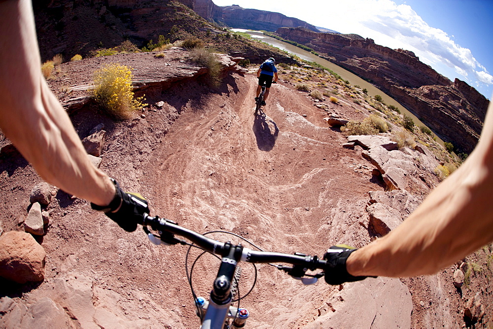 Mountain bikers riding on a trail overlooking the Colorado River near Moab Utah.