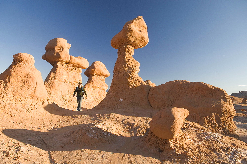 Woman hiking through hoodoos in Goblin Valley State Park, Hanksville, Utah.