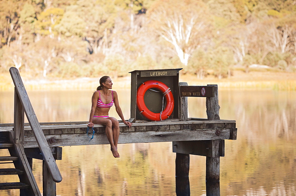 Sabina Allemann, 49 years old is sitting by Lake Catani wearing a bikini swimsuit early on 26th January 2012, Mount Buffalo National Park, Victoria, Australia.