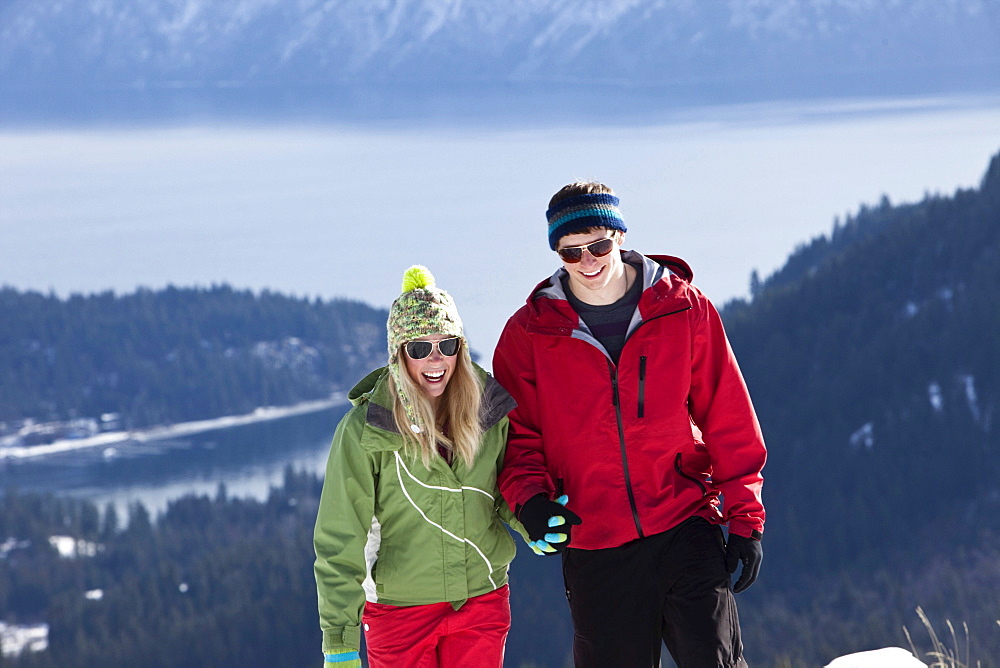 Two young adults smile while snowshoeing on a beautiful winter day in Sandpoint, Idaho.
