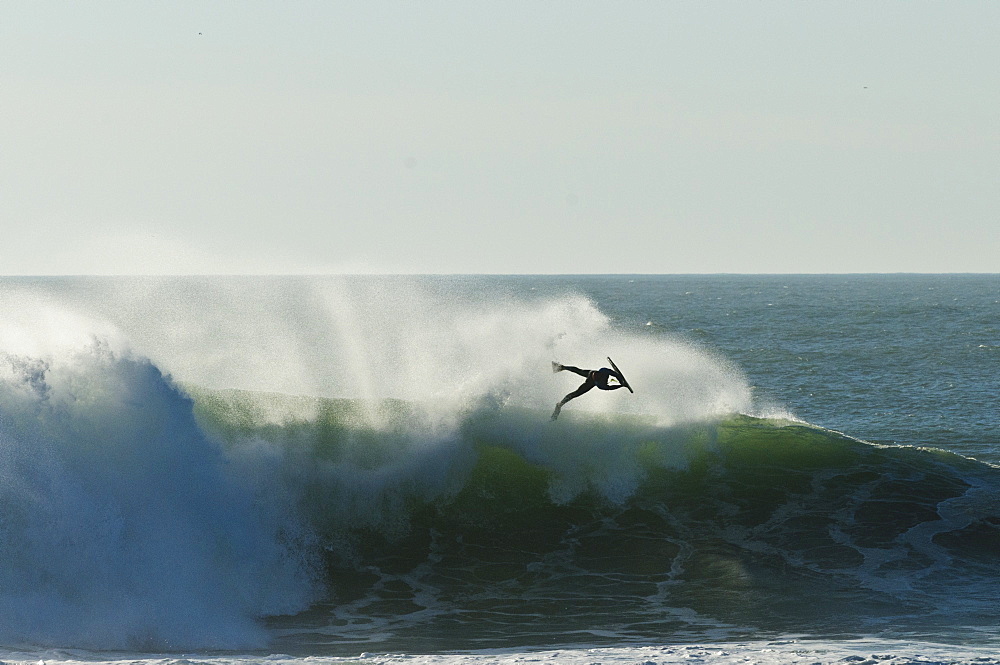 Bodyboarder does this aerial on a massive wave, backlite by sunset, at NAzare Special Edition contest, held in Nazare Portugal.