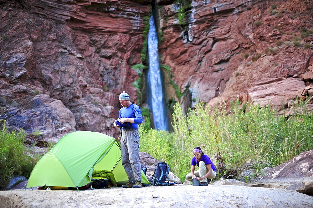 Hikers setup camp on a beach along the Colorado River near the plumeting 180-foot Deer Creek Falls in the Grand Canyon outside of Fredonia, Arizona November 2011.  The 21.4-mile loop starts at the Bill Hall trailhead on the North Rim and descends 2000-feet in 2.5-miles through Coconino Sandstone to the level Esplanada then descends further into the lower canyon through a break in the 400-foot-tall Redwall to access Surprise Valley.  Hikers connect Thunder River and Tapeats Creek to a route along the Colorado River and climb out Deer Creek.