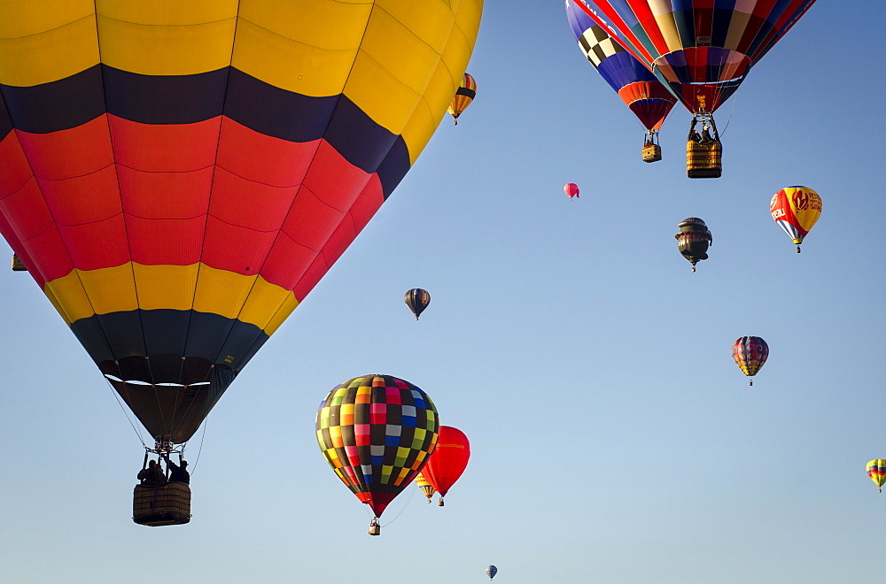 Hot air balloons lift skyward. The Albuquerque International Balloon Fiesta takes place in Albuquerque, New Mexico each year drawing in participants and spectators from across the globe. Highlights include an early morning dawn patrol, followed by mass ascencion of aircraft and an evening glow which all take place at the Balloon Fiesta Park throughout the week long event.