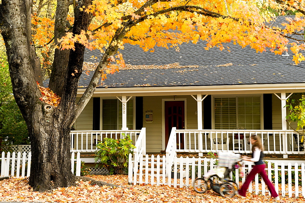 Mother pushing stroller in front of victorian house with fall leaves, Nevada City, California, Nevada City, California, USA