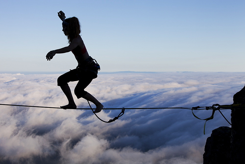 Silhouette of professional highliner Hayley Ashburn standing up on a highline above the clouds atop Mount Tamalpais, Marin County, California, United States