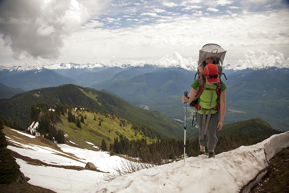 A woman carrying an infant hiking in the mountains. hiking in the mountains, Cascade Mountains, , Washington