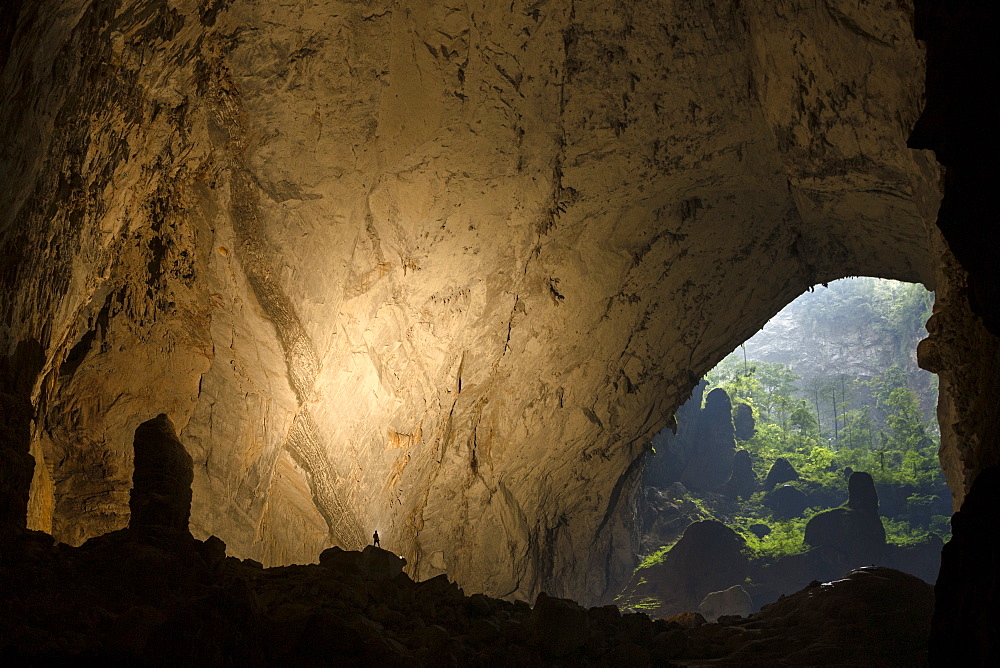 A cave explorer illuminates a large passage looking out towards the second doline in Hang Son Doong, Vietnam.