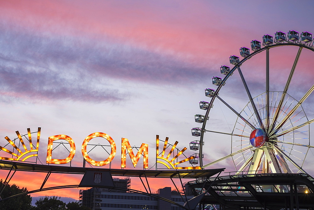 Illuminated entrance to Hamburger DOM funfair and ferris wheel at sunset, St. Pauli, Hamburg, Germany