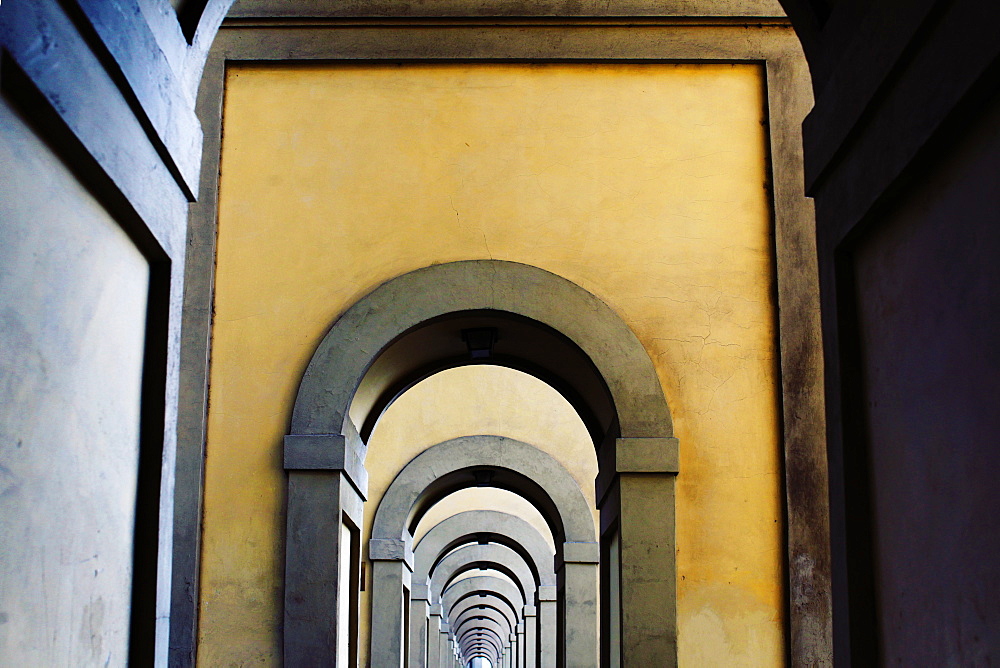 Arched medieval stone walkway found at the end of the Ponte Vecchio ("Old Bridge") next to the Arno River in Florence, or Firenze, Italy.