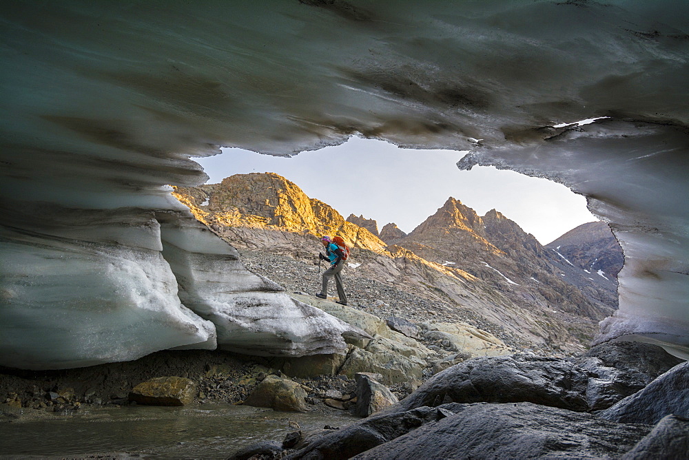 A woman hiking in front of glacial snout of ice in Titcomb Basin in the Wind River Range, Bridger Teton National Forest,  Pinedale, Wyoming.