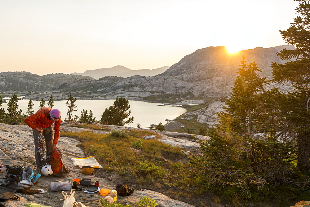 A woman packing up camp to head home after a week rock climbing in Titcomb Basin, Wind River Range, Bridger Teton National Forest,  Pinedale, Wyoming.