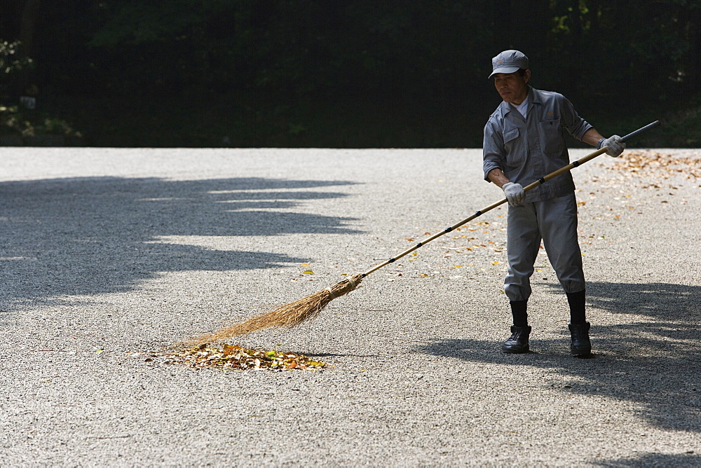 A man sweeping the walk way in a park, Tokyo, Japan.