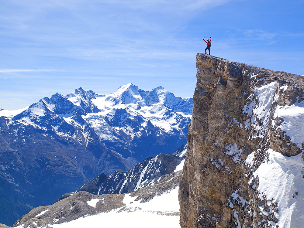 A male mountaineer is standing on the summit of the Barrhorn, a mountain peak of 3610 meter in the Swiss Alps. It is one of the highest summits in Europe to be accessible to experienced hikers. The region of Wallis is home to over 40 mountain peaks higher than 4000 meter. The highest one that is completely situated within the Swiss borders is the Dom, which is visible in the background. The Mattertal runs from Visp all the way to Zermatt and is a paradise for all outdoor enthusiasts, like hikers, climbers, alpinists, walkers, mountain bikers and nature lovers.