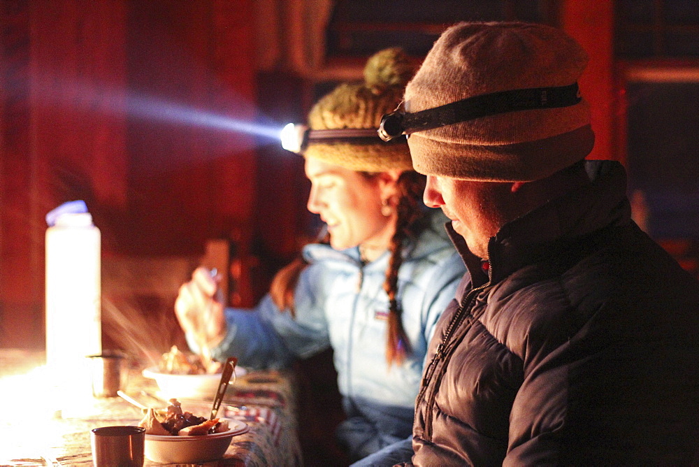 A young married couple eat Thanksgiving dinner inside a cabin in the Frank Church River of No Return Wilderness.