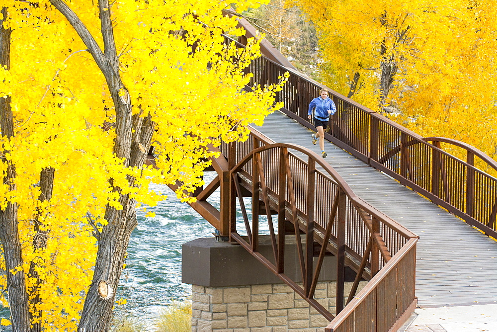 A woman running over the Animas River on a bridge on the Animas River Trail in Durango, Colorado.