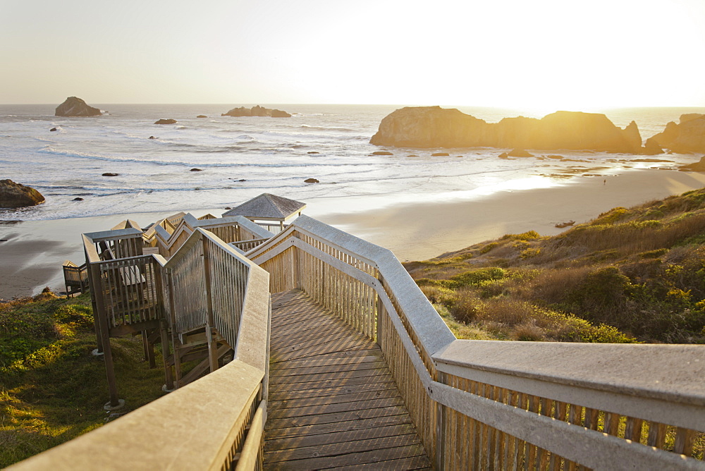 Evening light shines on a long wooden staircase leads down to Bandon Bay on the Oregon Coast.