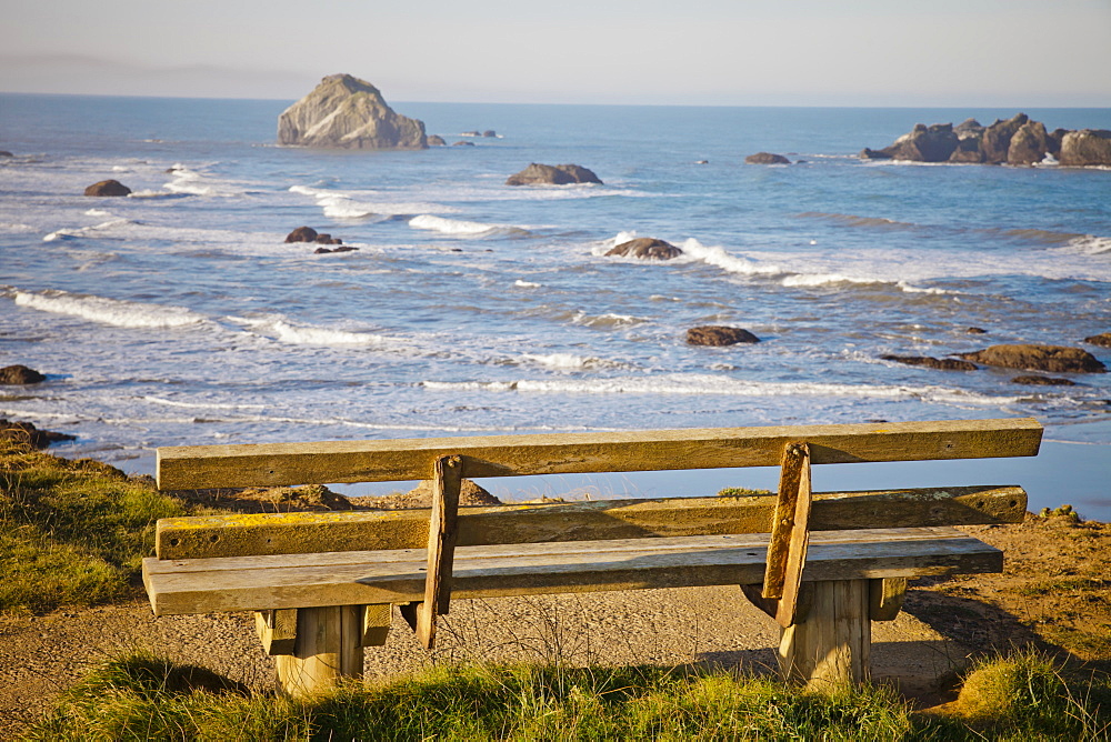 An old weathered wooden bench looks out at Bandon Bay, Oregon.