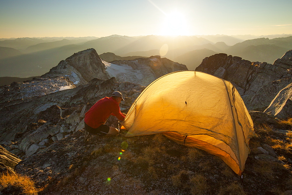 A hiker sets up a tent on the summit of Saxifrage Peak, Pemberton, BC, Canada.