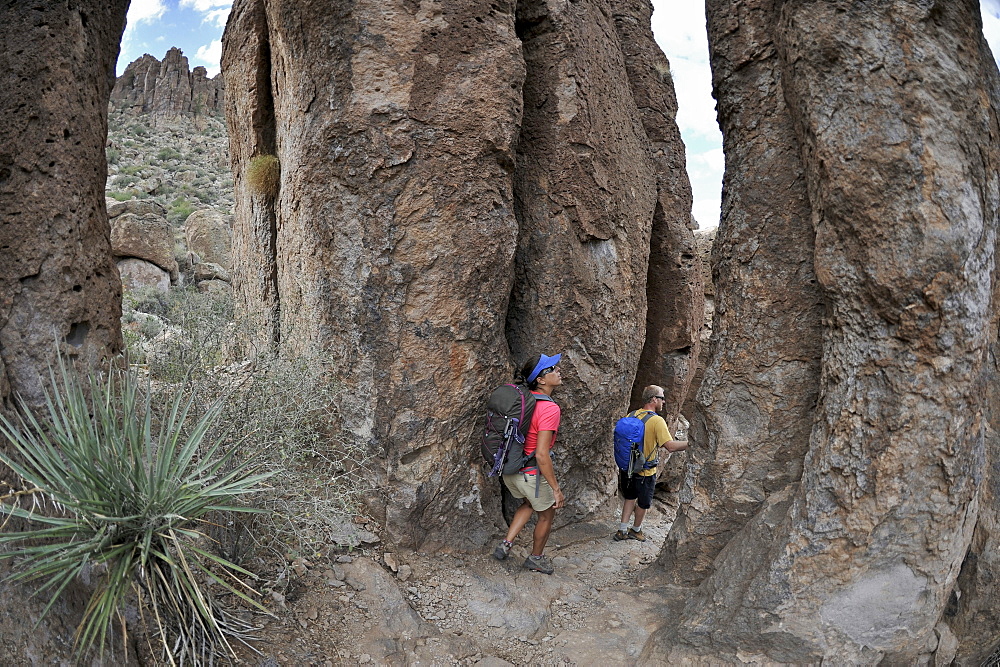 Man and woman backpackers explore the rock formations at Fremont Saddle on the popular Peralta Trail in the Superstition Wilderness Area, Tonto National Forest near Phoenix, Arizona November 2011.  The trail offers spectacular views of Weavers Needle and the rugged Sonoran desert.