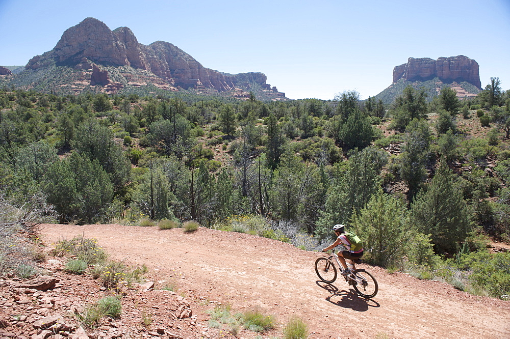 Woman rides the popular Bell Rock Pathway near Courthouse Butte in South Sedona, Arizona.  Bell Rock Pathway is a popular starting point to access Sedona's classic loop rides.