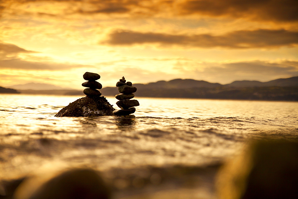 Two small rock stacks are slowly covered by water as the tide rises near Sechelt, BC, Canada.