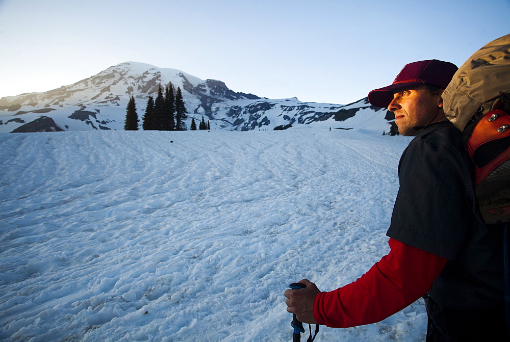 A young skier skins up a snowy slope on Mount Rainier at sunset, United States of America