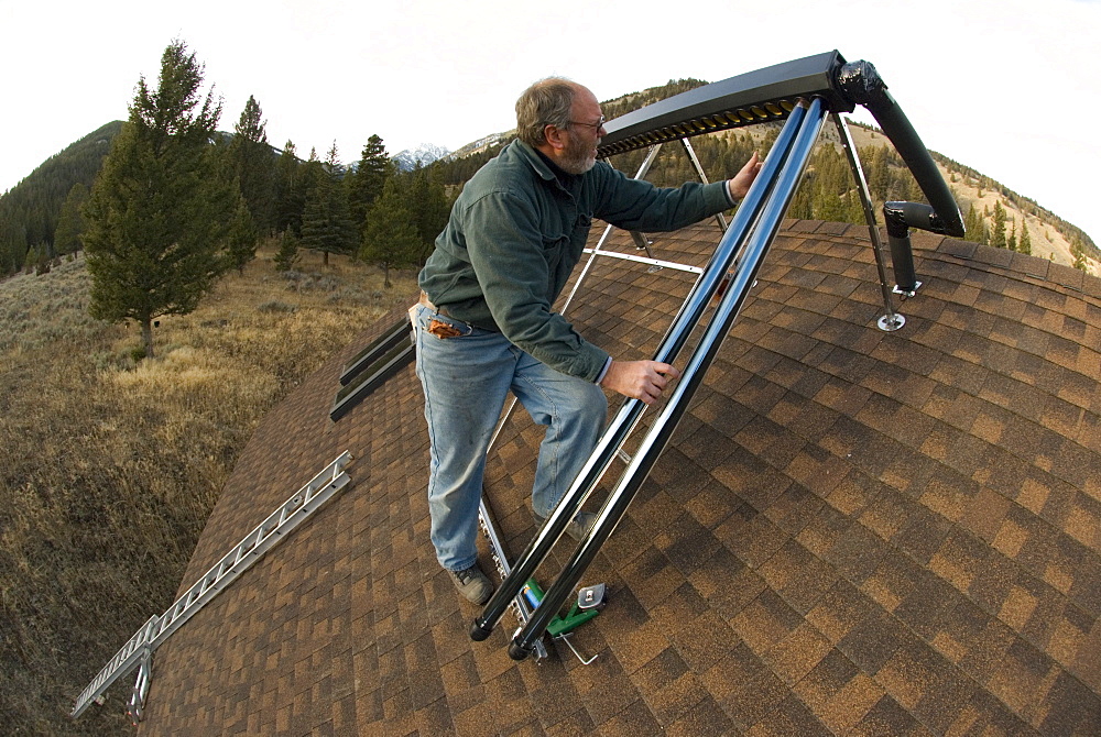 Mike McPherson installs an evacuated tube solar hot water system on a roof of a house near Big Sky, Montana, United States of America