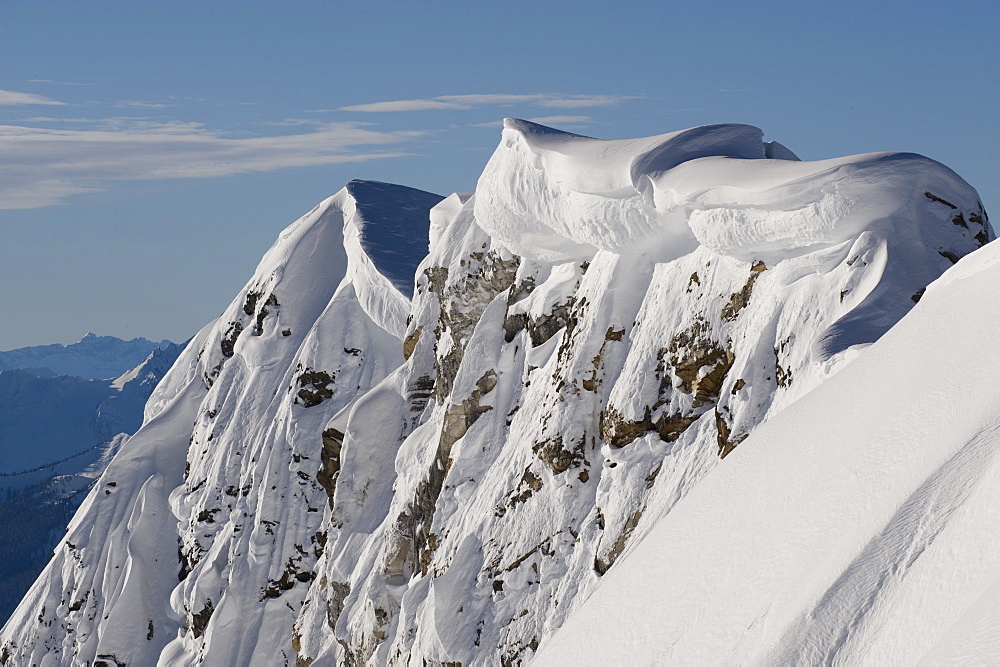 A mountain ridge holds heavy cornices from winter storms, Canada