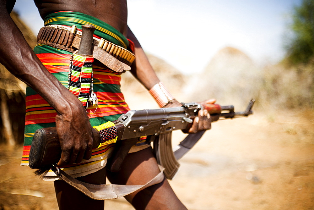 HAMER VILLAGE, OMO VALLEY, ETHIOPIA. An Ethiopian man holds a kalashnikov rifle at his waist, Ethiopia