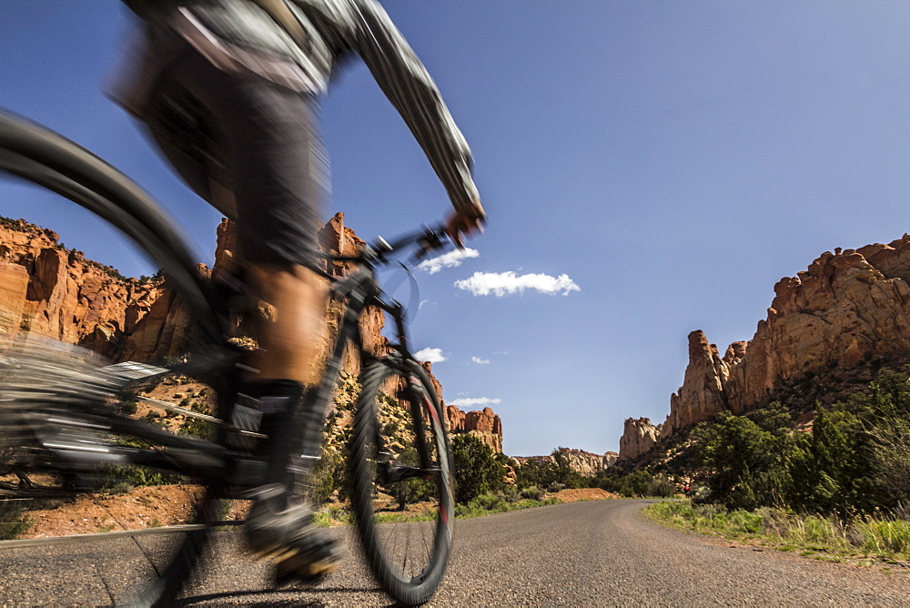 A mountain biker passes by in a blur on a road in southwest desert scenery.