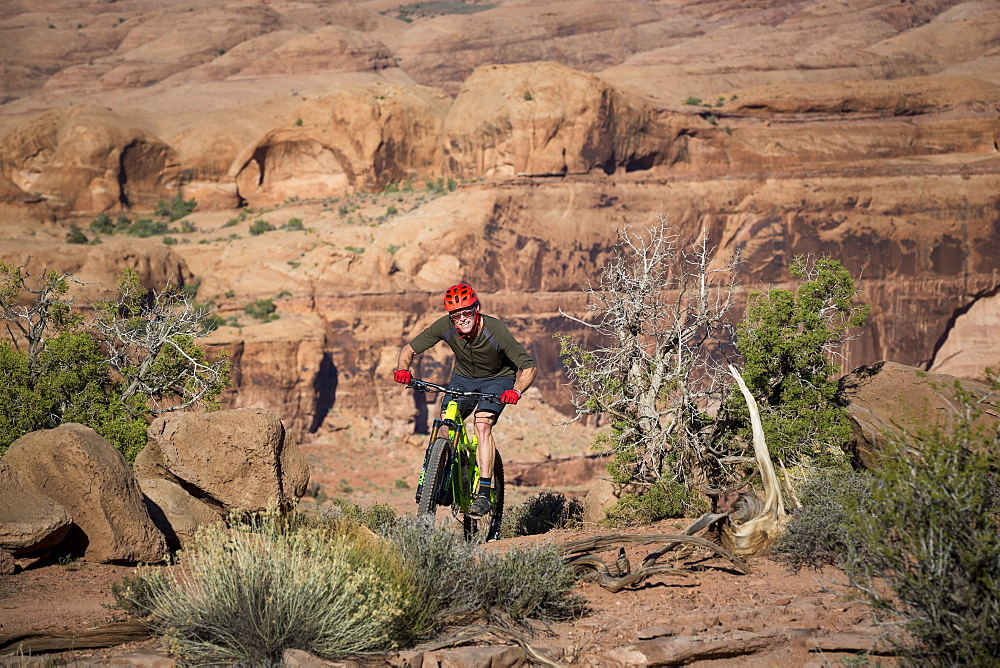 Man mountain biking on a trail in a desert environment.