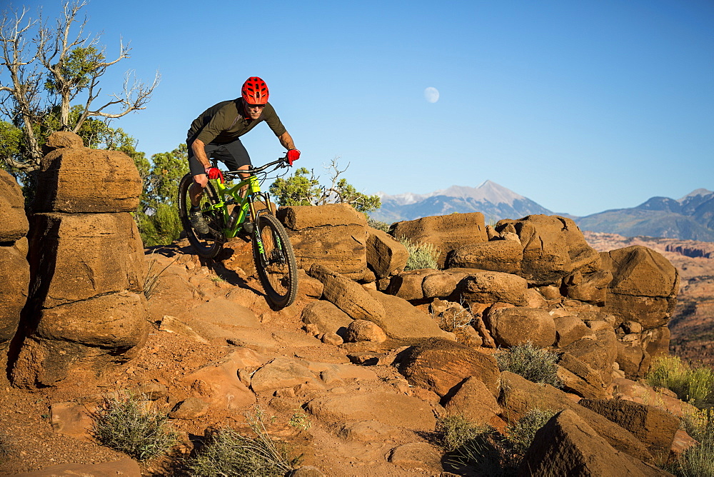 Man mountain biking on a trail in a desert environment.