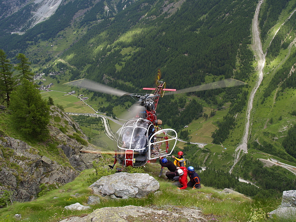 Mountain Rescue Personnel is carefully loading into a hovering helicopter.