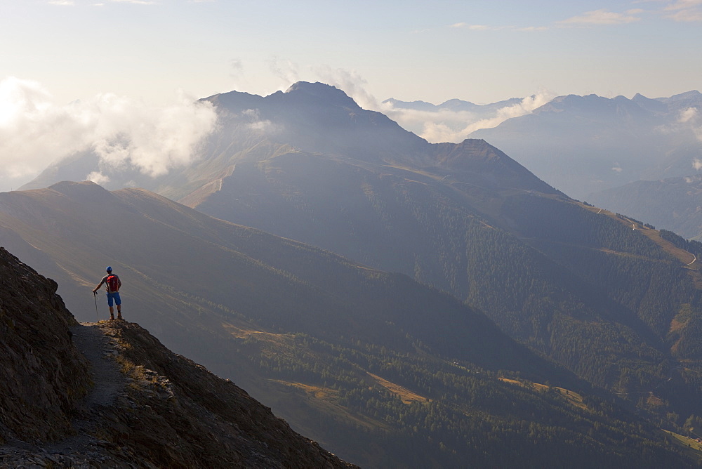 A male hiker enjoys the beautiful view over mountains and valleys, during the Glocknerrunde, a 7 stage trekking from Kaprun to Kals around the Grossglockner, the highest mountain of Austria.