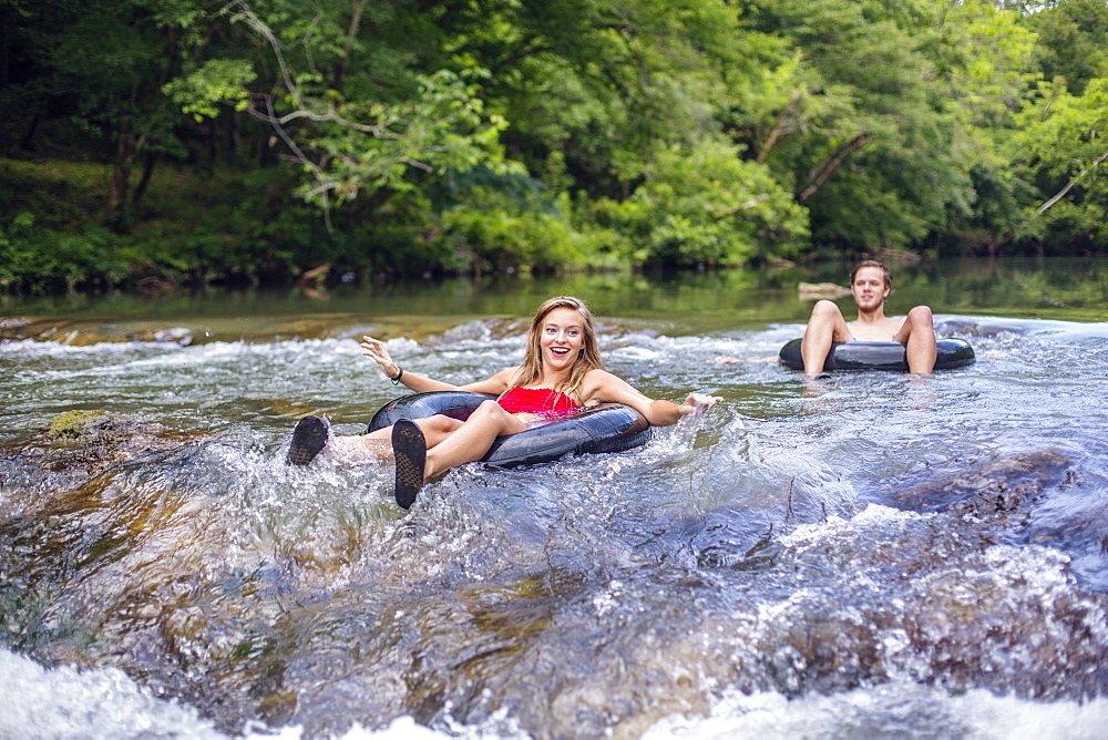 A young couple tubes down a river.