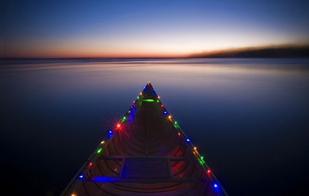 On a cold winter day a canoe decorated with Christmas lights floats on the last remaining open water on Lake Monona.