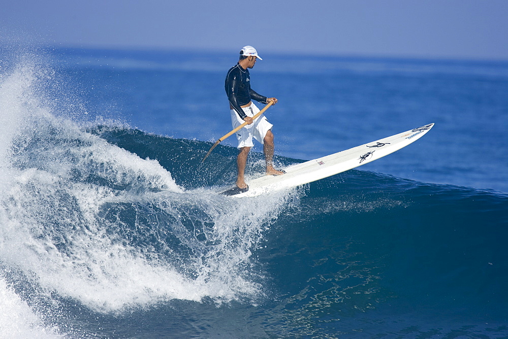 A man stand up paddle surfing at Pipeline on Oahu's north shore, 03.06.07