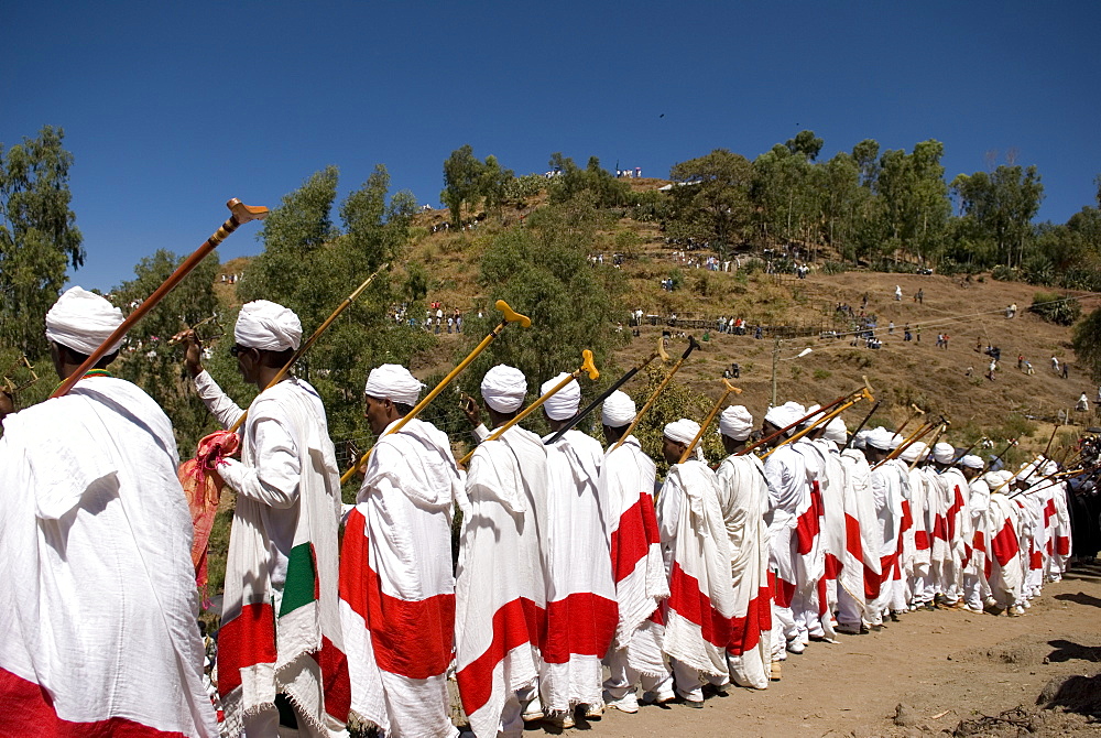 Group of priests dressed in ceremonial clothes chanting and dancing in procession during Timkat festival in Lalibela, Ethiopia