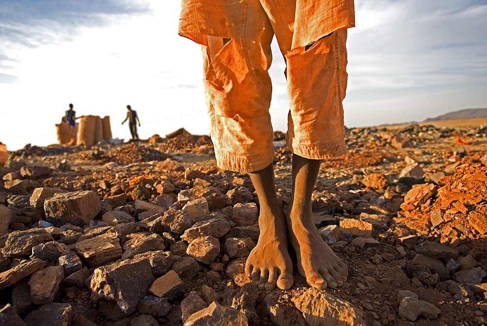 A barefoot goldmine worker stands near a shaft in Sudan.