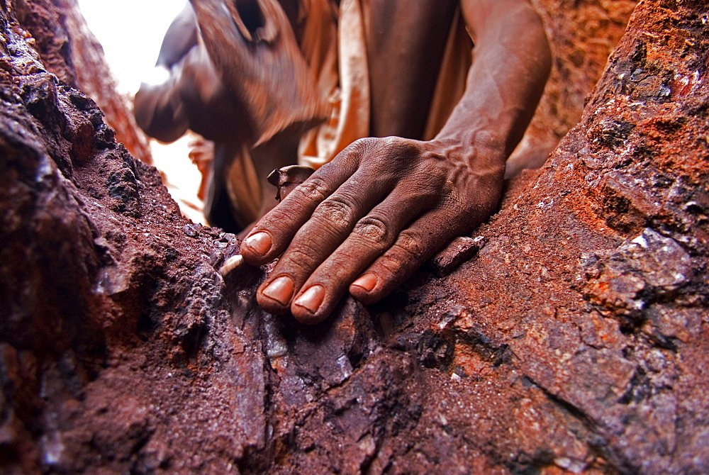 A gold miner works in a shaft using hand tools in Sudan.