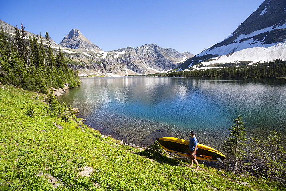 A man carries a portable stand up paddle board (SUP) at Hidden Lake in Glacier National Park.