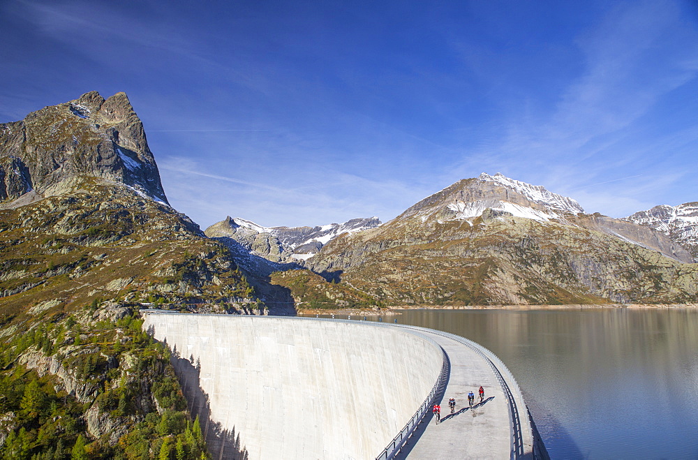 Four road bikers on the dam of the Emosson reservoir lake in the Alps on the border of France and Switzerland. It is an early morning training session of the local cyclists. The climb from Martigny to Finhaut will be stage 17 of the 2016 Tour de France on July 20th 2016. Depart is in Bern and the finish near the Emosson reservoir, Lac d'Emosson, at 1960 meters height.