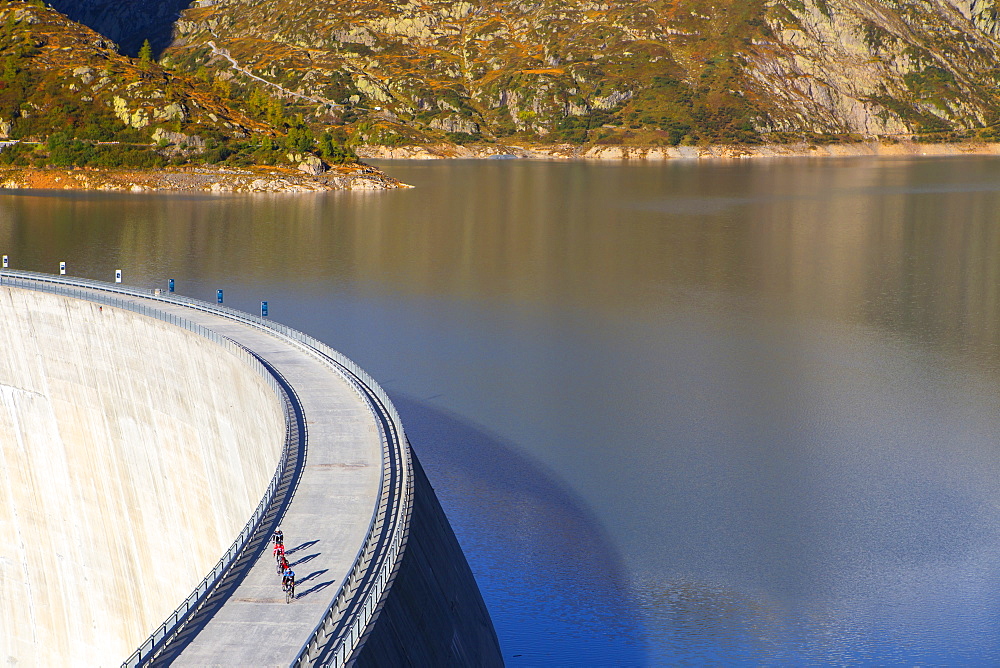 Four road bikers on the dam of the Emosson reservoir lake in the Alps on the border of France and Switzerland. It is an early morning training session of the local cyclists. The climb from Martigny to Finhaut will be stage 17 of the 2016 Tour de France on July 20th 2016. Depart is in Bern and the finish near the Emosson reservoir, Lac d'Emosson, at 1960 meters height.