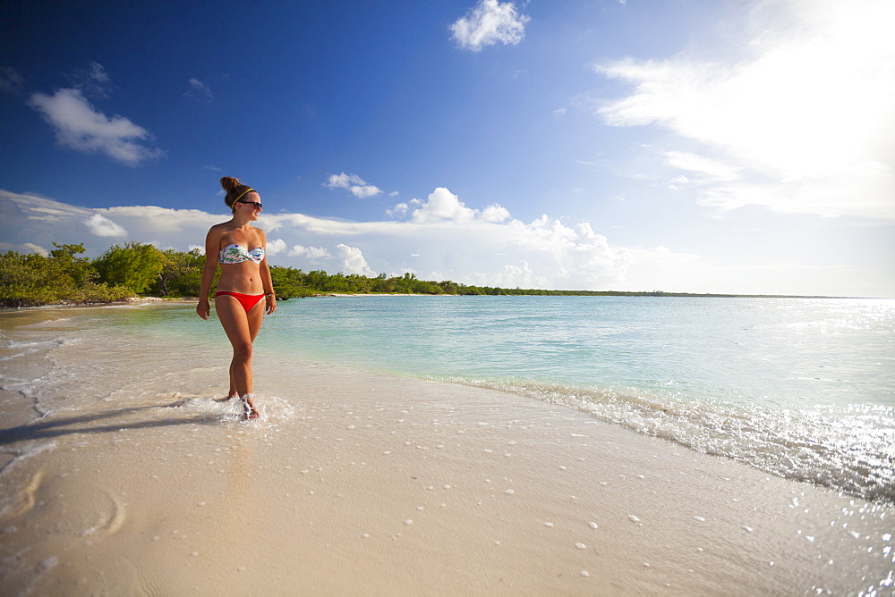 A young attractive woman walks on the beach in Cayo Coco, Cuba.
