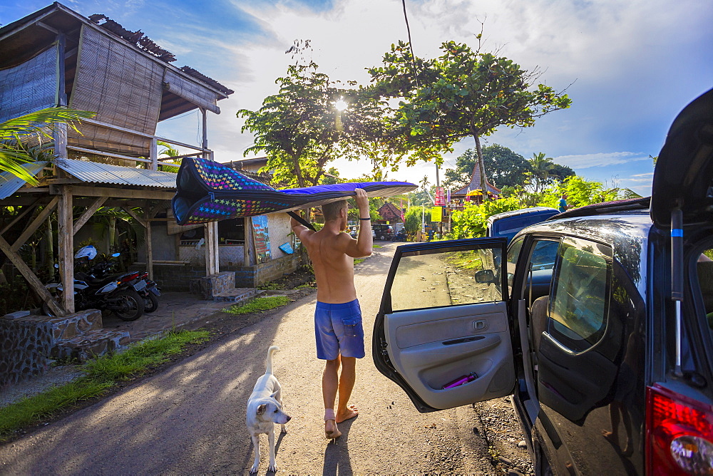 Surfer with a board at morning time, Balian village, Bali,  Indonesia