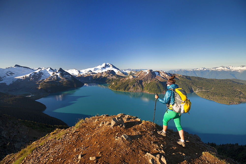 A backpacker reaches the summit of Panorama Ridge, overlooking Garibaldi Lake in Garibaldi Provincial Park, British Columbia, Canada.