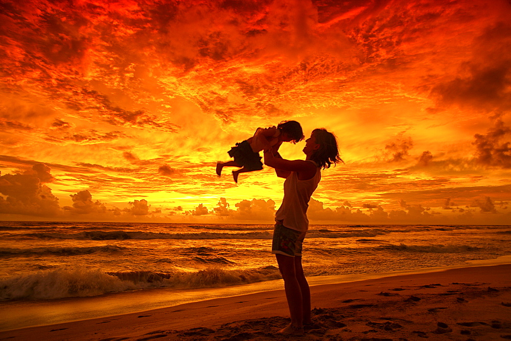 Mother and baby watching sunset on beach, near Unawatuna; Thalpe, Sri Lanka