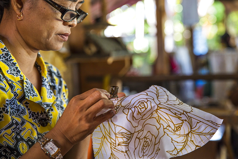 An Indonesian woman paints batik by hand in Ubud, Bali